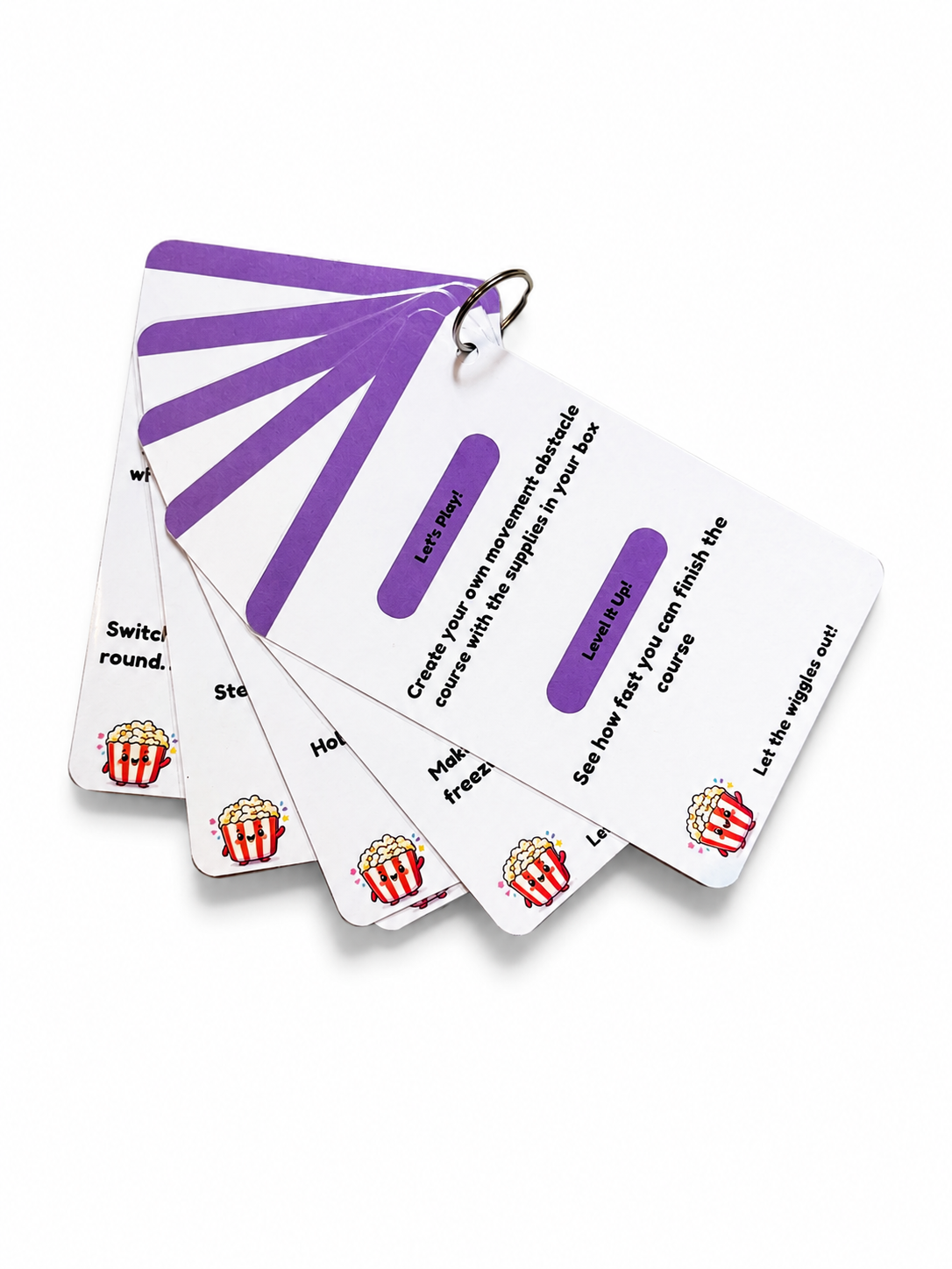 A fanned-out set of white learning cards with purple labels and red-and-white striped popcorn bucket graphics, attached to a metal ring on a white background.