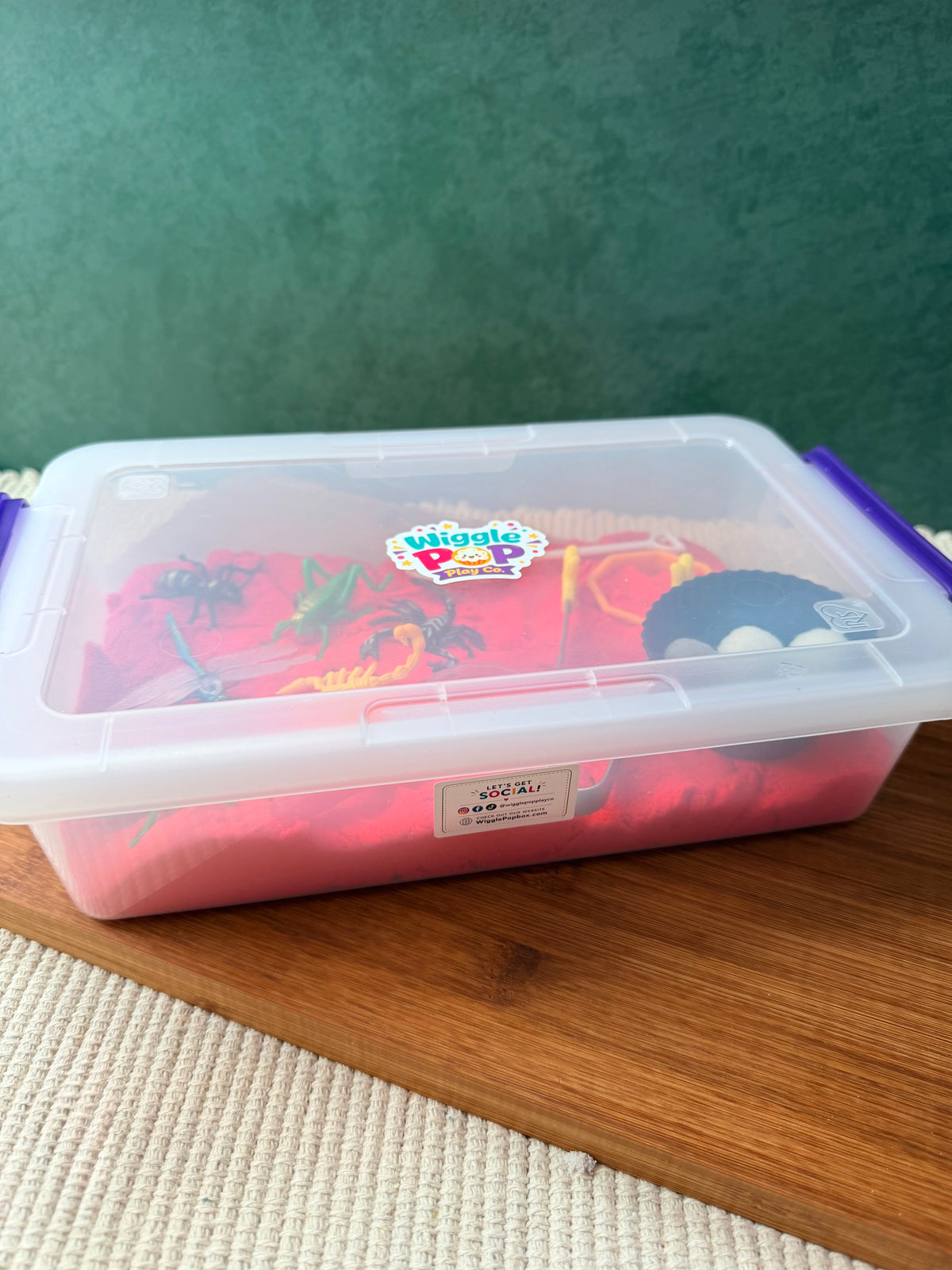 Nature themed sensory bin with red kinetic sand