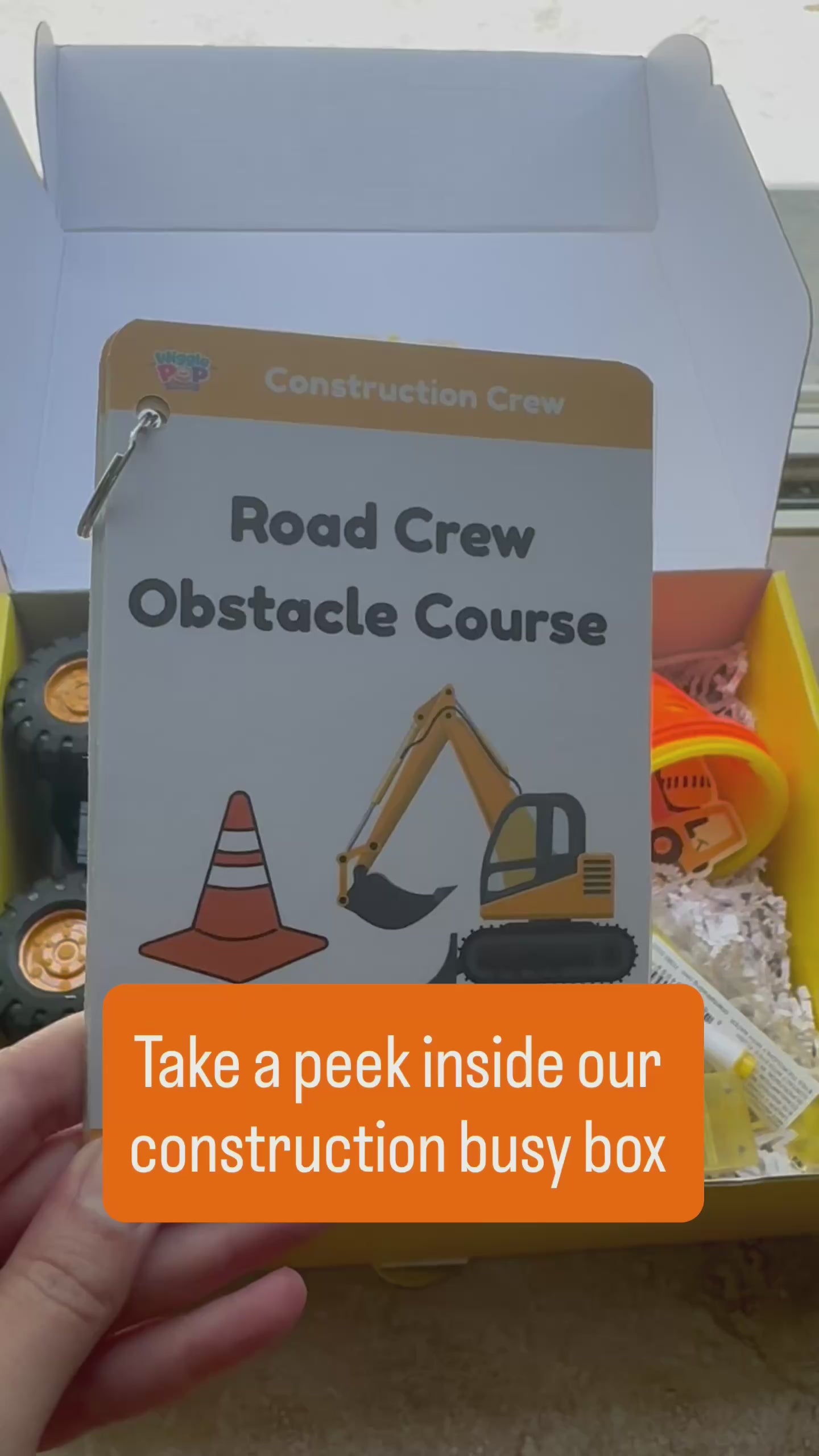 Video of construction themed activity box showing the supplies inside the box including cones, bubble wand, dump tuck, construction vehicle, road tape, activity cards